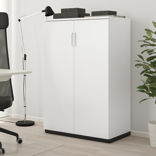 Mueble GALANT blanco de 2 puertas, tablero de partículas, junto a silla y lámpara.