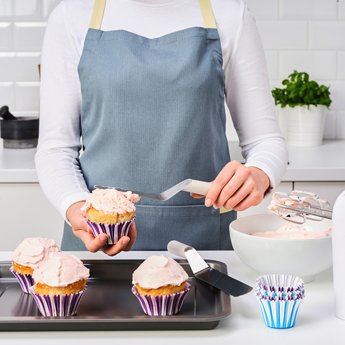 Una persona está glaseando cupcakes con una espátula en una cocina.
