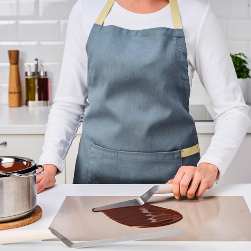 Un chef usa una espátula acodada para untar chocolate derretido, lo que demuestra su uso en la repostería.