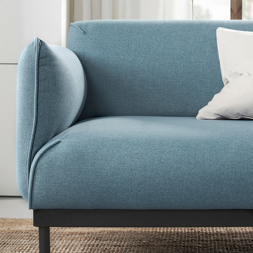 Moderno sofá de tela azul con almohada cilíndrica y cojín blanco, con líneas elegantes y asientos cómodos.