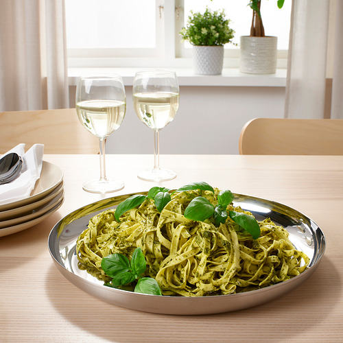 Plato de pasta emplatado con copas de vino sobre una mesa de madera.