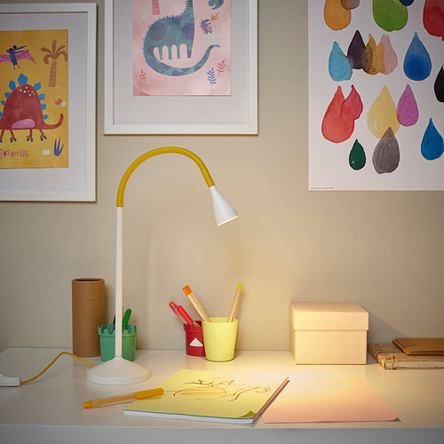 La lámpara de escritorio ilumina el espacio de trabajo con materiales de arte y decoración minimalista.