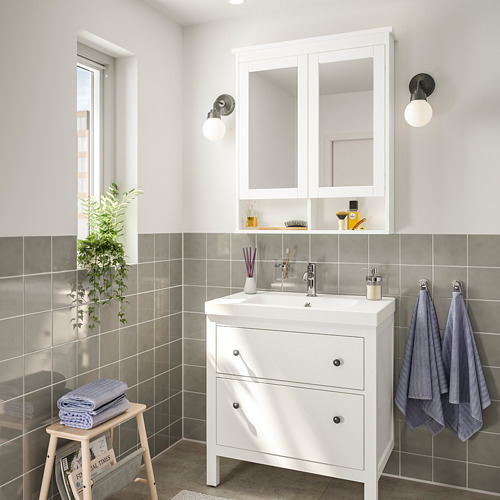 Baño moderno con tocador HEMNES, gabinete con espejo y toallas azules.