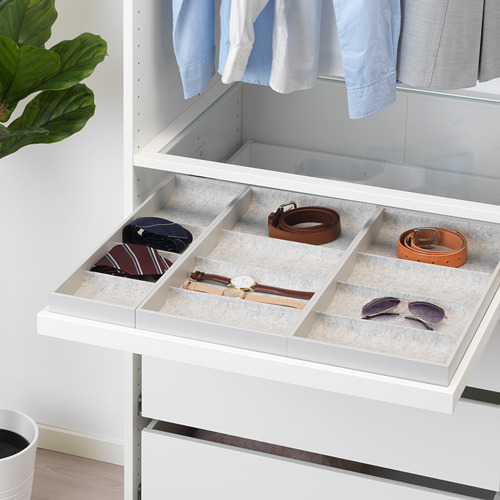 Cajón de armario blanco con inserciones de fieltro gris que organizan los accesorios: cinturones, corbatas, reloj y gafas de sol.