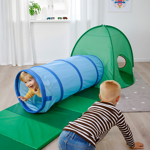 Niños jugando con una carpa emergente verde y un túnel de juego azul.