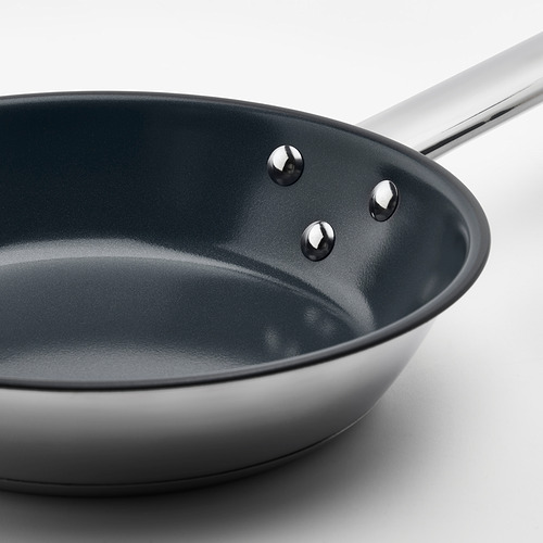 Una sartén de ikea de alta calidad con un interior antiadherente oscuro, un mango resistente de acero inoxidable y tres remaches que aseguran el mango a la sartén.