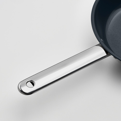 Primer plano del mango de la sartén de acero inoxidable, diseño elegante, unido de forma segura a la sartén.