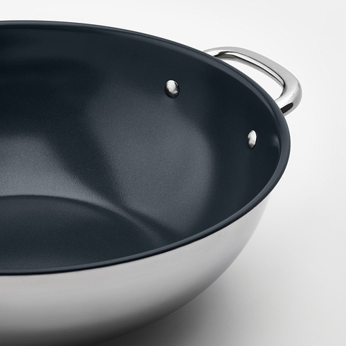Primer plano de un elegante wok con interior antiadherente, mango de acero inoxidable, exterior pulido.