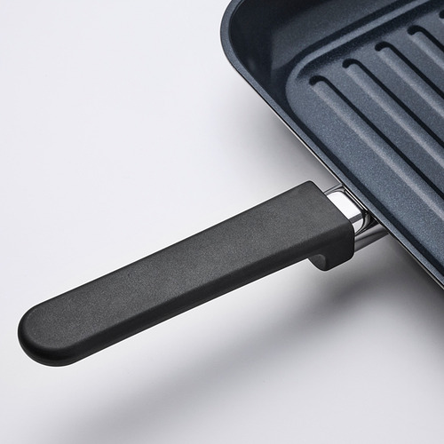 Primer plano del mango de la sartén de la parrilla MIDDAGSMAT, que muestra un diseño robusto y materiales duraderos.
