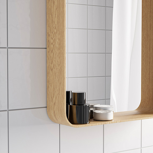 Un espejo con marco de madera y un estante que muestra dos artículos. Está diseñado para colgar vertical u horizontalmente, perfecto para baños.