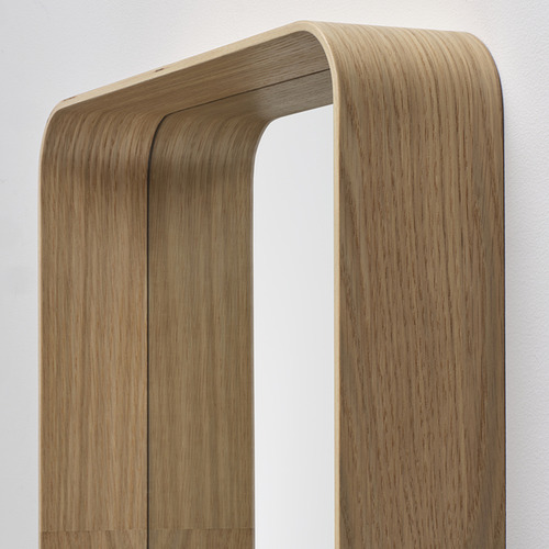 Espejo con marco de madera en la pared, con un elegante acabado en roble y sutiles curvas, que reflejan un diseño de alta calidad.