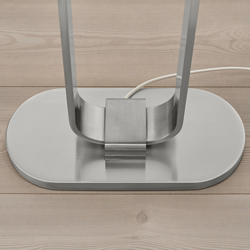 Lámpara de pie metálica moderna con base sobre suelo de madera. Alternativamente: lámpara de pie de metal resistente sobre suelo de madera.