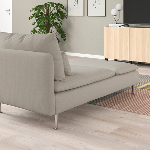 Una elegante tumbona SÖDERHAMN gris claro con asiento y respaldo acolchados, colocada contra una pared con una planta y una alfombra colorida cerca.