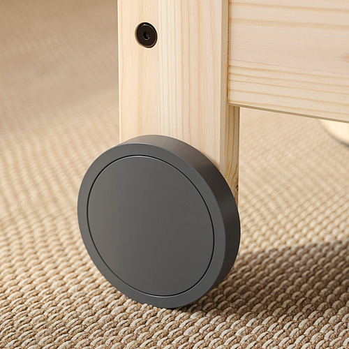 Gris oscuro, cerradura de suelo redonda sobre pata de mueble de madera, suelo alfombrado.