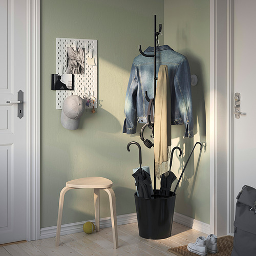 El perchero negro de ÄLGANÄS, elegante y alegre, se adapta a espacios pequeños. Taburete de madera y puertas blancas cerca.