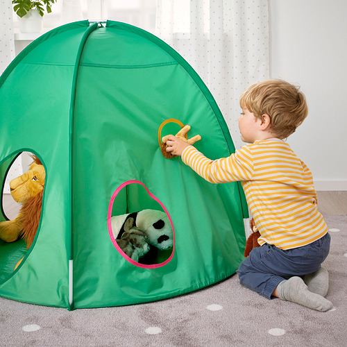Niño jugando con carpa emergente verde. Un niño con camisa a rayas abre la solapa de la tienda, revelando animales de peluche en el interior.