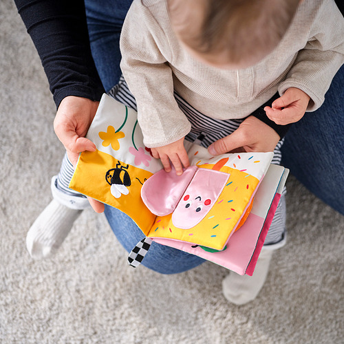 Adultos y niños leyendo un libro de jugadas suave e interactivo con figuras de tela, texturas y sensores.