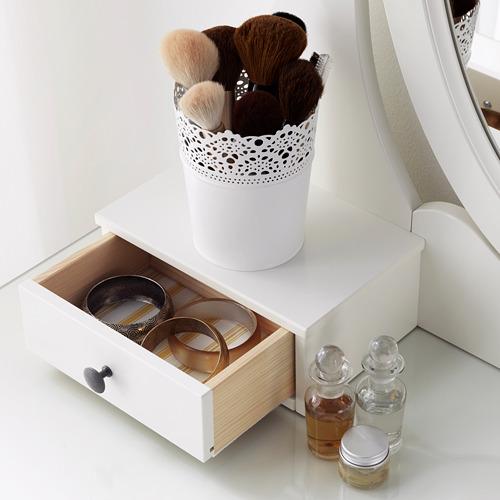 Tocador blanco con cajón abierto que muestra joyeros y soporte para anillos, perfumes y soporte para brochas de maquillaje en la parte superior.