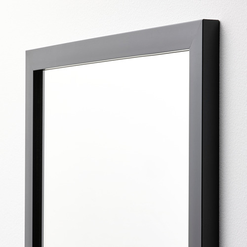 Espejo de pared moderno con elegante marco negro, que se refleja limpiamente, montado de forma segura en la pared de color claro.