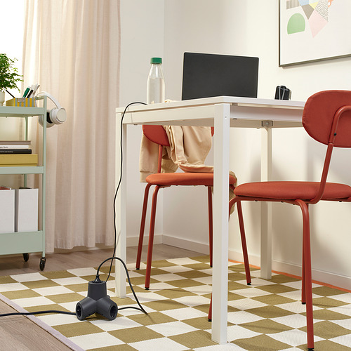 Oficina en casa con ordenador portátil, botella, auriculares y cable de extensión HORNFELS sobre escritorio blanco. Silla roja al frente.