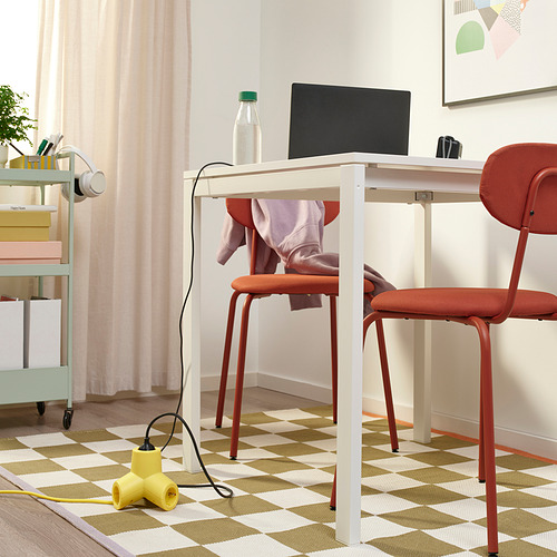 Oficina en casa con escritorio, computadora portátil, silla roja y cable de alimentación amarillo.