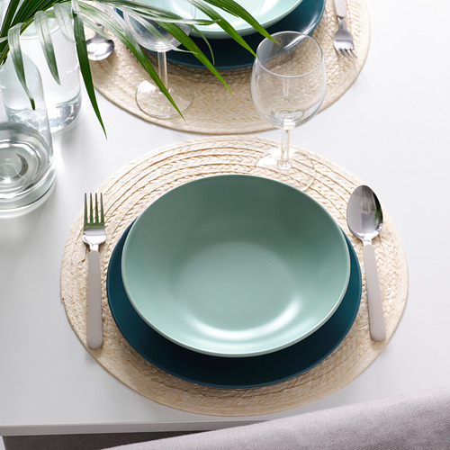 Mesa con platos FÄRGKLAR de color verde intenso, manteles individuales naturales, cubiertos y vasos.