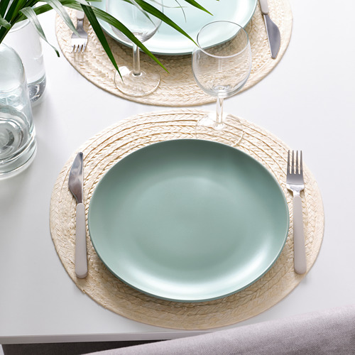 Dos cubiertos con platos verdes FÄRGKLAR, cubiertos, vasos y manteles individuales tejidos sobre un mantel blanco.