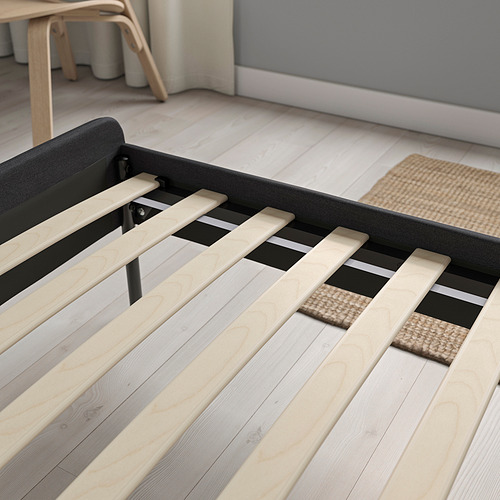Una moderna estructura de cama con listones de madera y cabecero acolchado, tapizado en tela gris, diseñado para un fácil montaje y almacenamiento debajo de la cama.