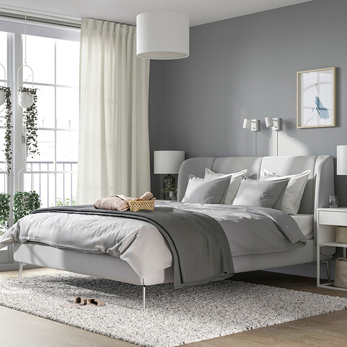 Dormitorio moderno: cama TUFJORD gris con cabecera tapizada, sábanas grises, alfombra blanca y plantas colgantes. Suave, grande, acogedor.