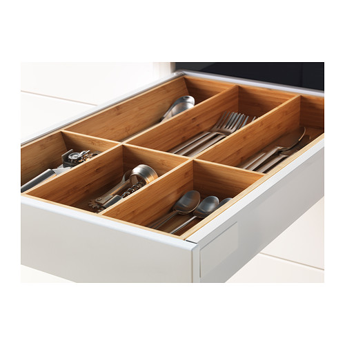 Cajón de cocina abierto con compartimentos de madera para utensilios que contienen cubiertos.