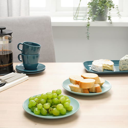 Juego de mesa con platos auxiliares, tazas y comida de FÄRKKLAR. Un ambiente acogedor con pan, uvas y café.