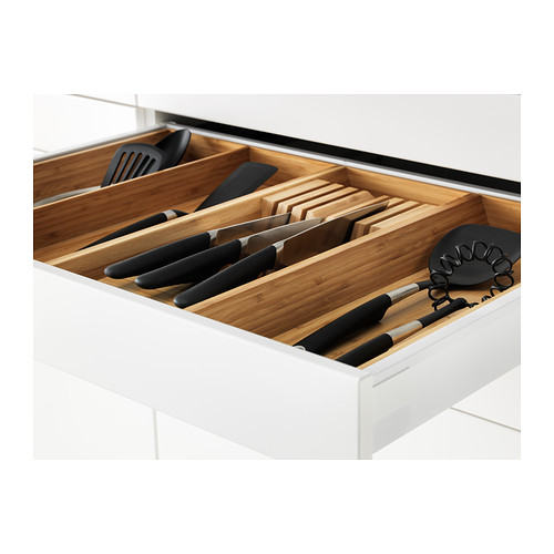 Cajón de cocina blanco abierto que muestra cuchillos organizados, tablas de cortar y utensilios en compartimentos.
