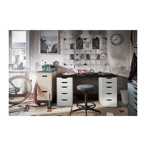 Espacio de trabajo de estilo industrial: escritorio blanco LAGKAPTEN con dos cajones, una silla de oficina negra y varios elementos decorativos.