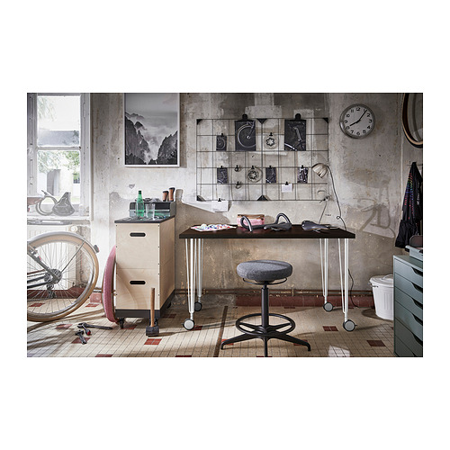 Espacio de trabajo de estilo industrial con mesa LAGKAPTEN, con tablero de madera, patas de metal, sillas y elementos decorativos.