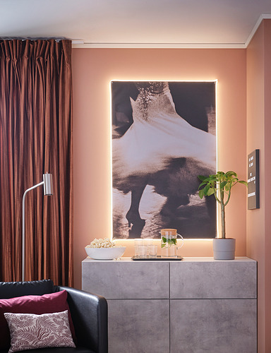 Salón moderno con aparador BESTÅ, estampado artístico y silla negra.