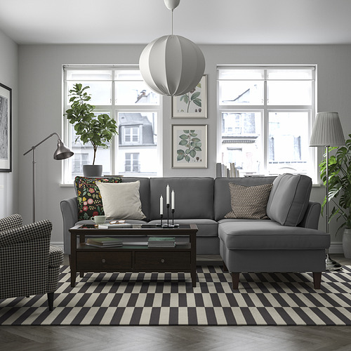 Sofá modular EKHOLMA gris con líneas limpias, cojines, luz natural, plantas y almohadas de colores.