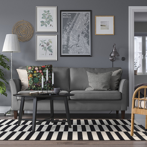 Acogedora sala de estar moderna con sofá EKHOLMA gris, mesa de centro negra, alfombra en blanco y negro y arte de pared. El sofá encaja bien debajo de grandes impresiones artísticas.