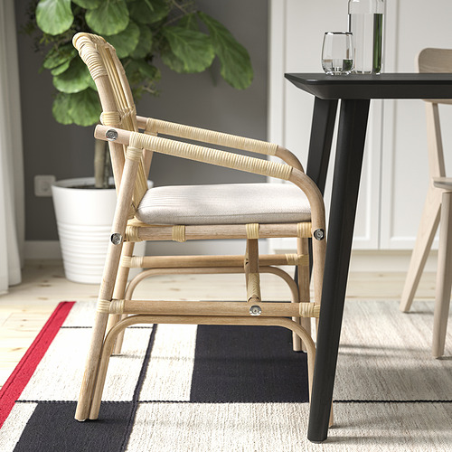 Una silla de madera ligera con un asiento acolchado se asienta sobre una alfombra a cuadros.