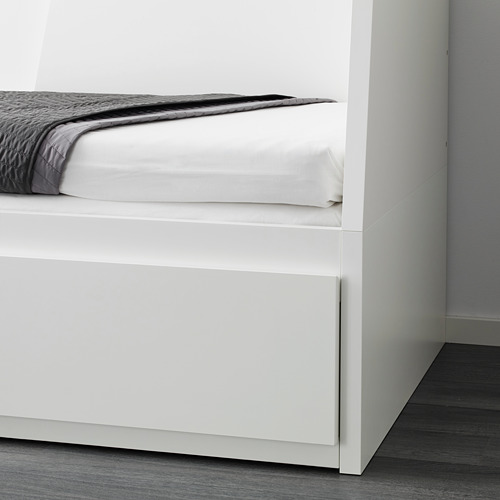Sofá cama blanco con una manta doblada en un extremo, mostrando su doble funcionalidad como sofá y cama.
