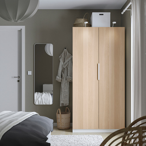Dormitorio minimalista con armario PAX, espejo y cesta.