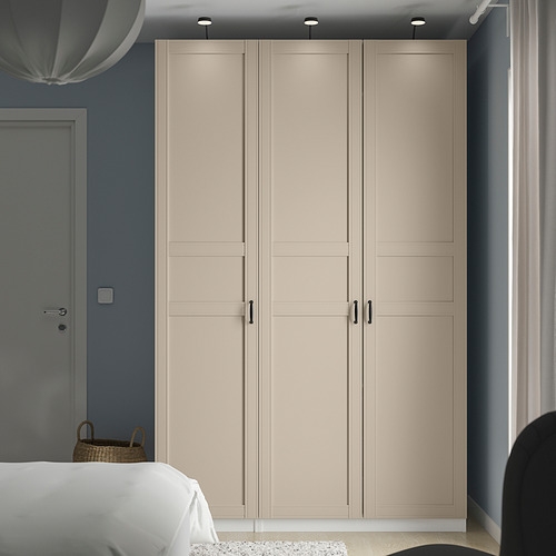 Armario PAX beige con tiradores negros e iluminación entre puerta y ventana.