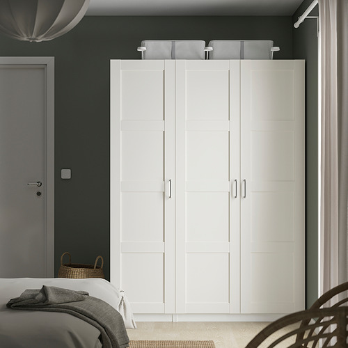 Moderno armario blanco PAX, alto con cuatro puertas, junto a la cama.