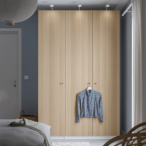 Dormitorio minimalista con armario de madera PAX, iluminación, camisa, cama, cesta.