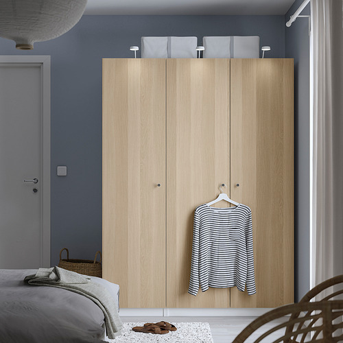 Dormitorio minimalista con armario PAX de madera clara, camisa de rayas, cesta de mimbre y alfombra blanca.