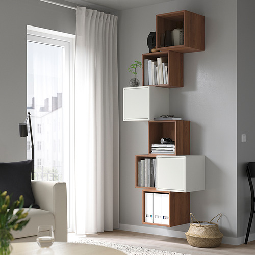 Salón moderno con muebles minimalistas: estanterías EKET, sofá beige, lámpara de pie y cesta.