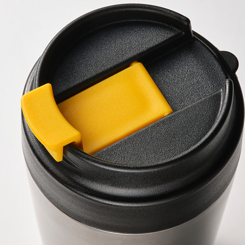 Primer plano de una taza de viaje de acero inoxidable con una tapa negra a prueba de fugas y un sello de silicona amarillo brillante, diseñada para un transporte seguro y sin derrames.