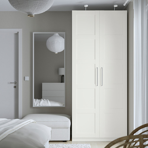 Dormitorio minimalista con amplio armario PAX, espejo, cama, banco blanco y lámparas colgantes.