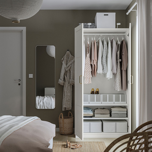 Dormitorio bien organizado con armario PAX, con ropa, ropa doblada y cajas de almacenamiento. Un espejo y perchas son visibles.
