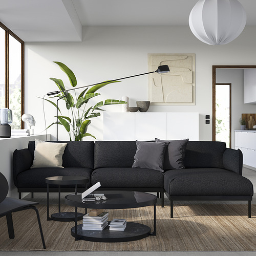 Salón moderno con sofá ÄPPLARYD gris, almohadas, mesas negras, planta, arte, lámpara colgante, suelo de madera.