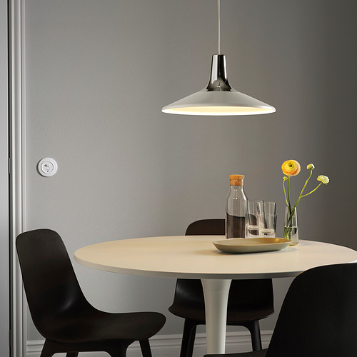 Comedor moderno con lámpara FYRTIOFYRA sobre mesa redonda con flores amarillas.